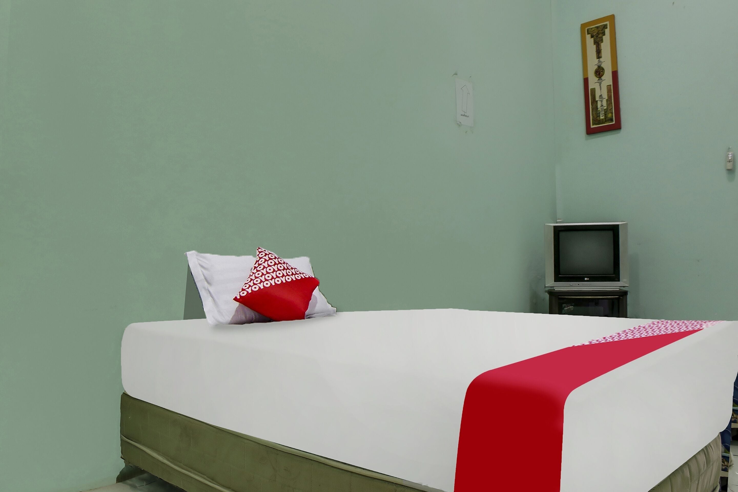A room with a bed, a television, and a wall-mounted picture.