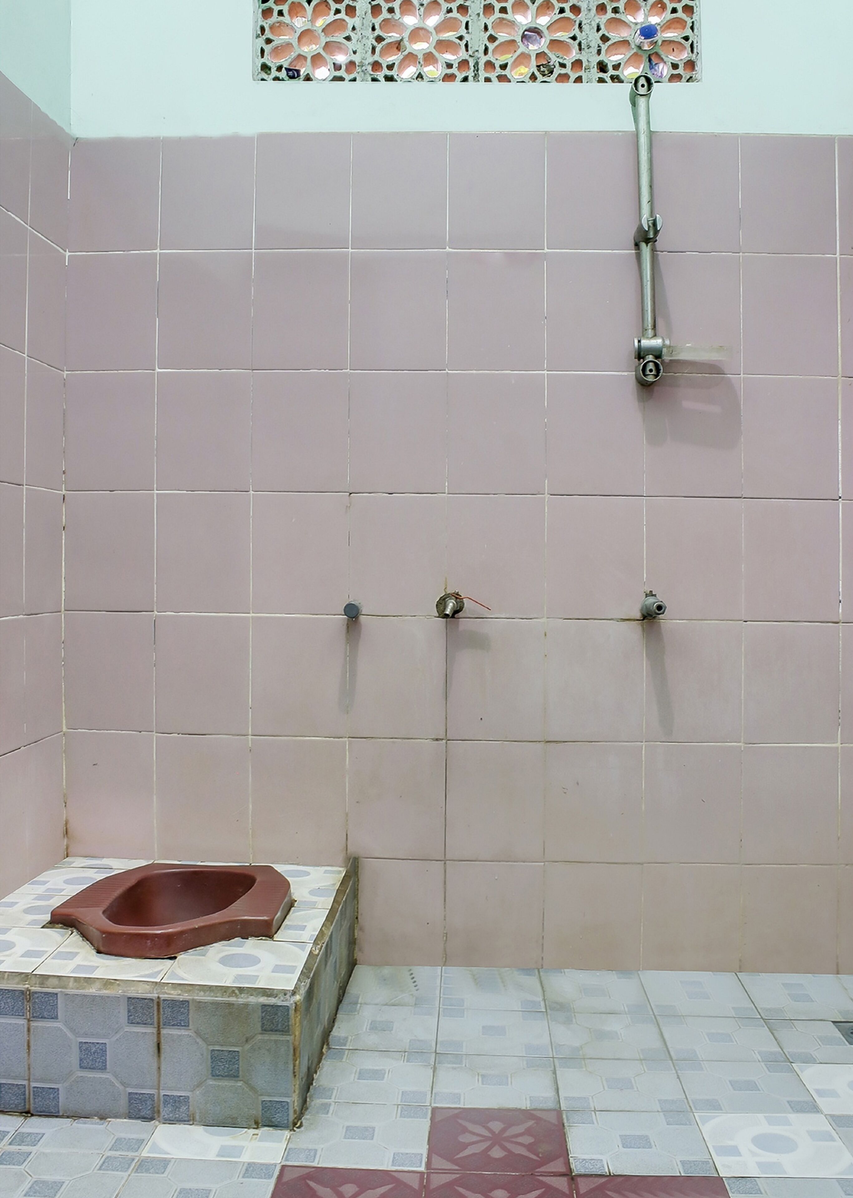 Un baño con inodoro, ducha y suelo de baldosas.