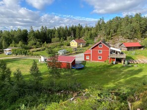 A rural landscape with a red barn, a yellow house, and a green field. - 2 Person Holiday Home in Henan (Henån)
