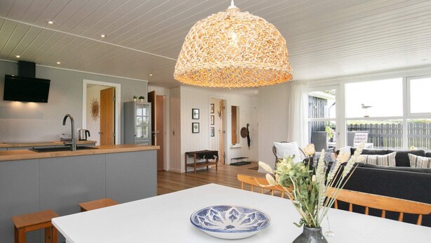 Une cuisine moderne avec un plan de travail blanc, un évier encastré et un luminaire suspendu.