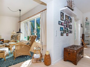 Una habitación con muebles de mimbre, un cofre de madera y una pared decorada con cuadros.