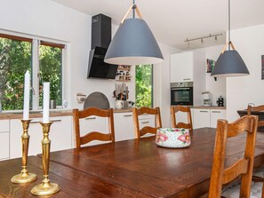 Una cocina moderna con armarios blancos, una mesa de comedor de madera y luces colgantes.