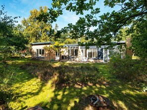 Una casa moderna con un patio, una fogata y un jardín.