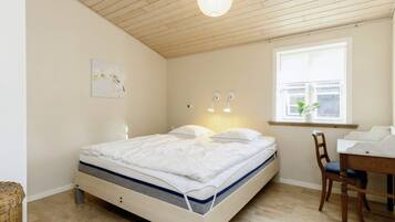 A bedroom with a bed, a desk, a chair, a window, and a ceiling light.