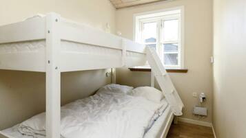 A bunk bed room with a window, a power outlet, and a wall socket.