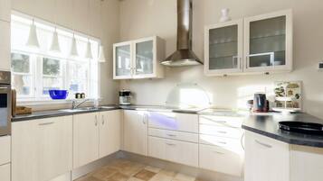 A modern kitchen with white cabinets, a black countertop, and a window providing natural light.