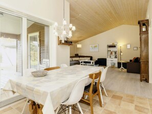 Un coin repas avec une table dressée pour quatre personnes, entourée de chaises blanches. On aperçoit un buffet en bois et un globe terrestre accroché au mur.