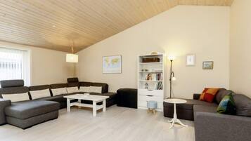 A modern living room with a sectional sofa, a white coffee table, a bookshelf, and a floor lamp.