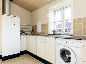 A compact kitchen with a washing machine, a refrigerator, and a window providing natural light. - 6 Person Holiday Home in Nysted (Nysted)