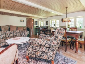 A spacious living room with a high ceiling, a dining area with a wooden table, and a kitchen in the background. - 4 Person Holiday Home in Laeso (Læsø)