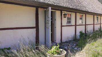 A traditional building with a thatched roof, a wooden door, and a small garden area with a potted plant.