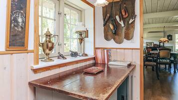 A rustic kitchen with wooden countertops, a window with a view, and various kitchen utensils hanging on the wall.