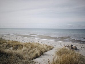 A beach with sand and grass, leading to the sea.