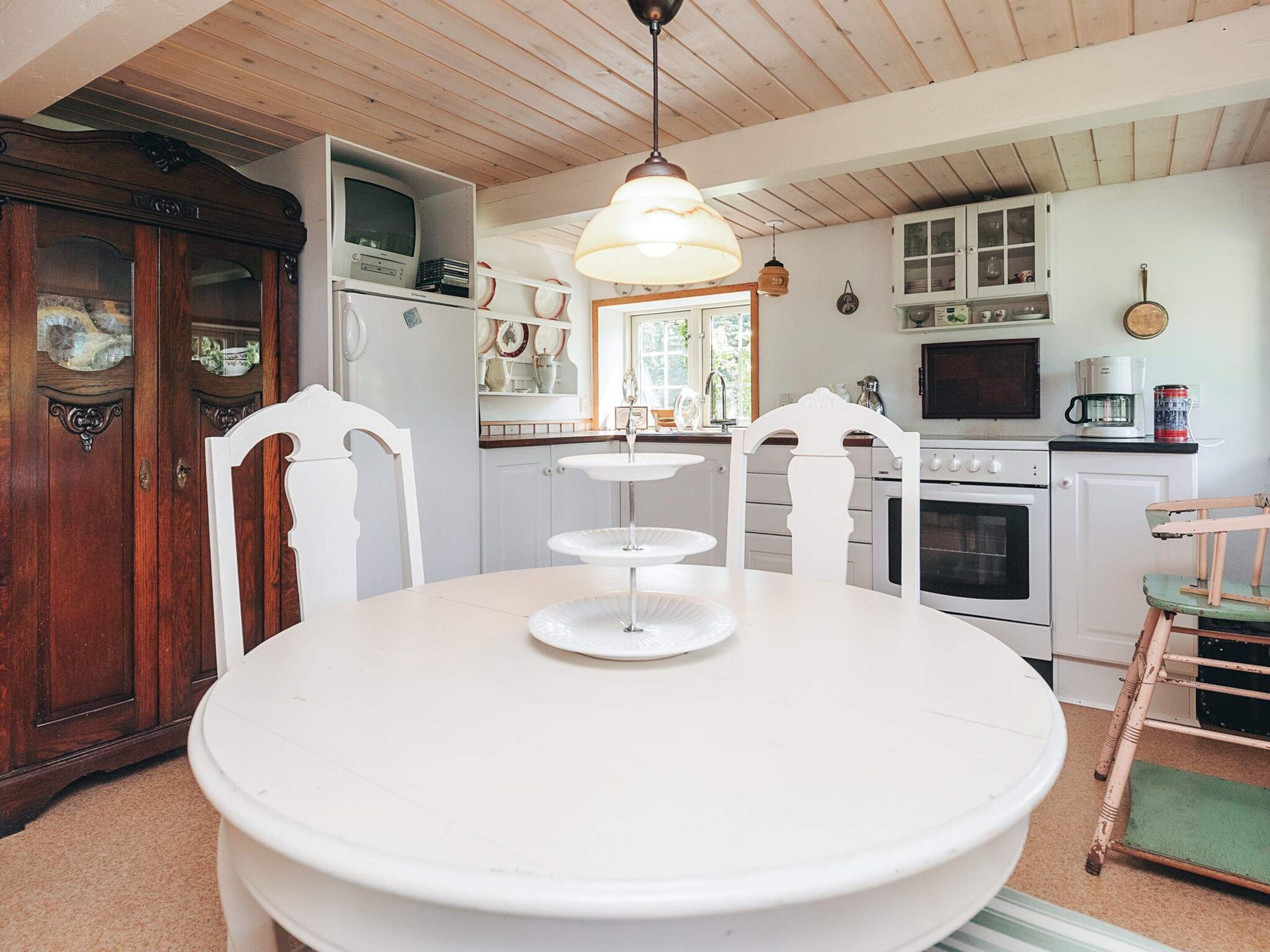 A kitchen with white cabinets, a stove, and a dining table with chairs.