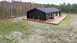 A modern black cabin with a deck and outdoor seating area. - 8 Person Holiday Home in Laeso (Læsø)