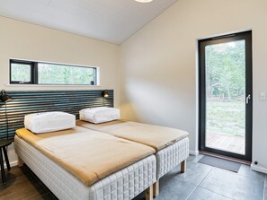 Une chambre avec deux lits, une fenêtre et une porte donnant sur un espace extérieur.