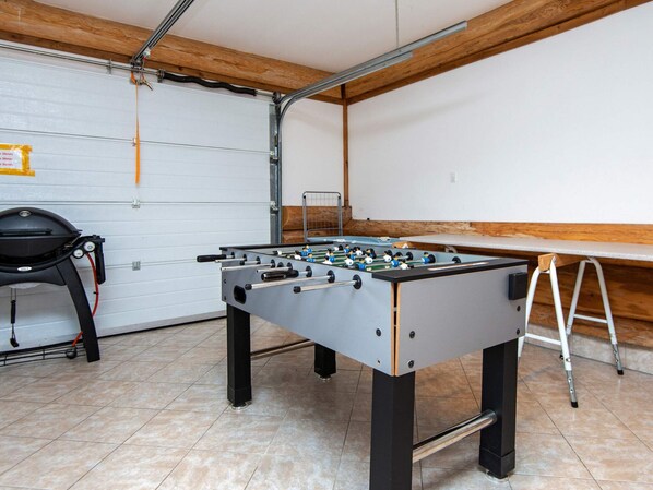 A room with a foosball table, a chair, and a ladder.