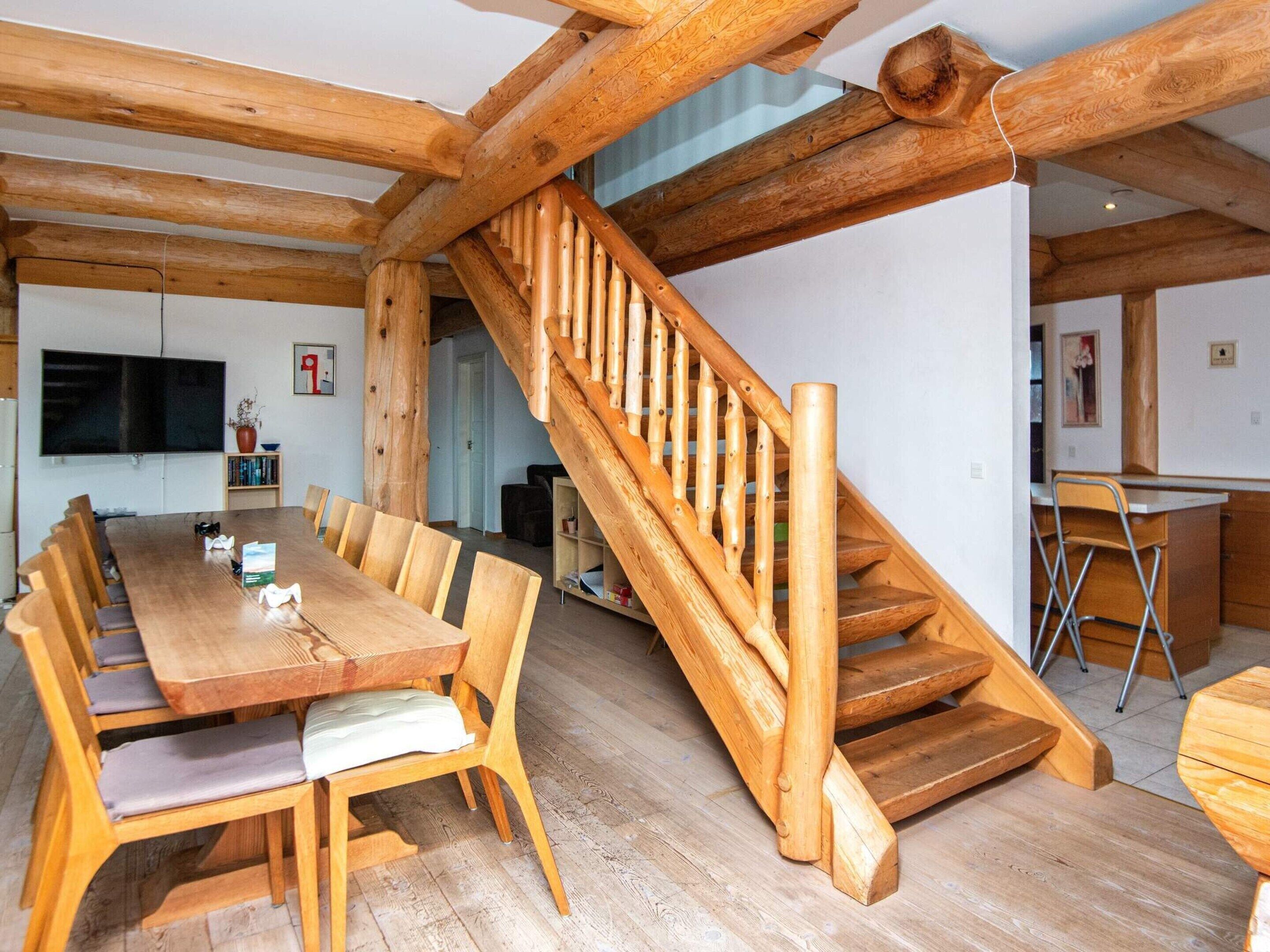 A wooden interior with a dining area, staircase, and kitchen.