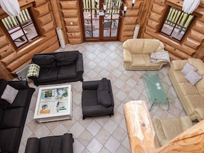 A log cabin interior with a tiled floor, two sofas, a coffee table, and a wooden table. - 5 Star Holiday Home in Nimtofte (Nimtofte)