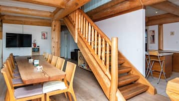 A wooden interior with a dining area, staircase, and kitchen.