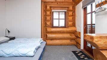 A log cabin bedroom with a bed, a desk, and a window.