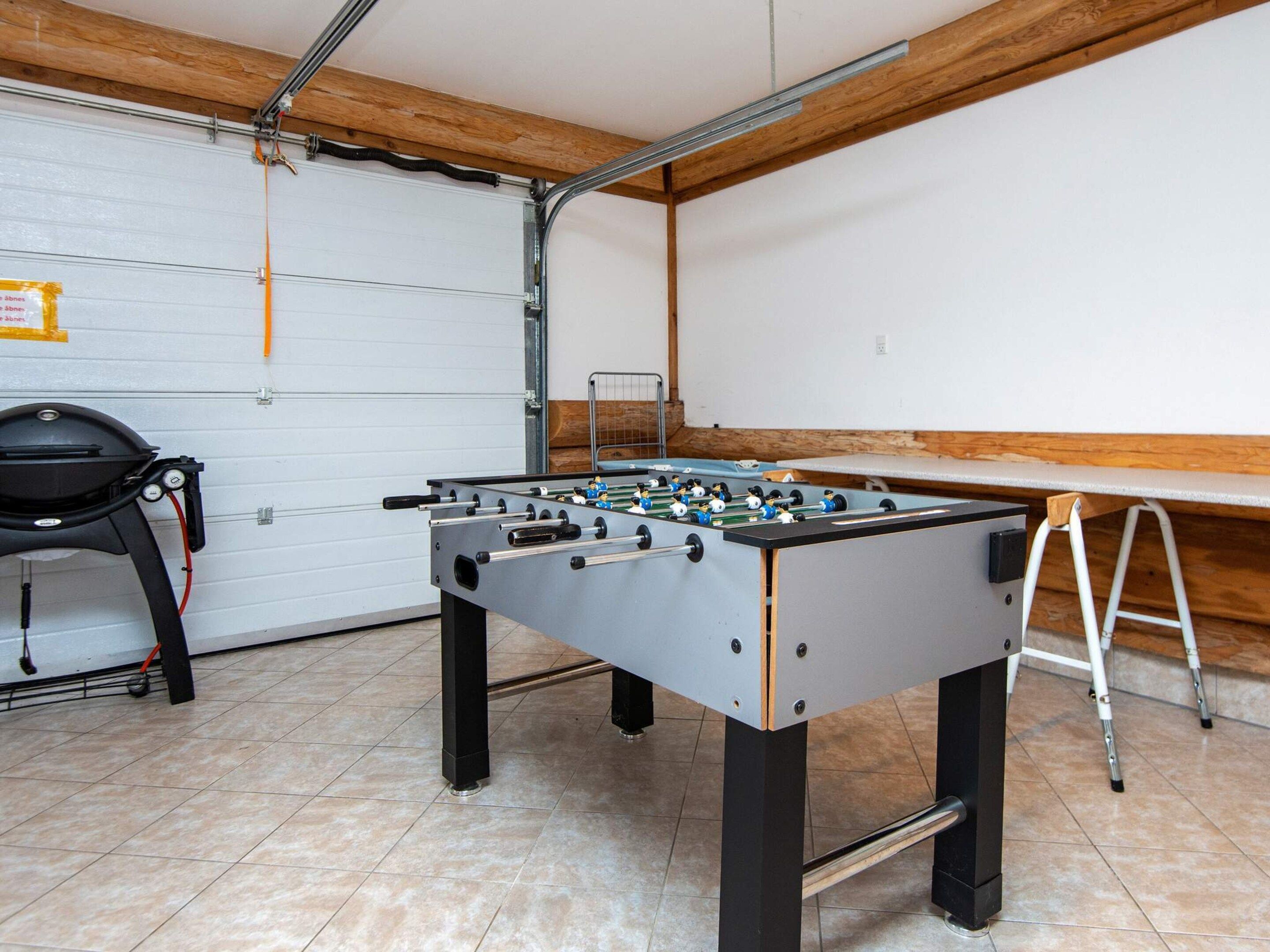 Una habitación con una mesa de fútbol, una silla y una escalera.
