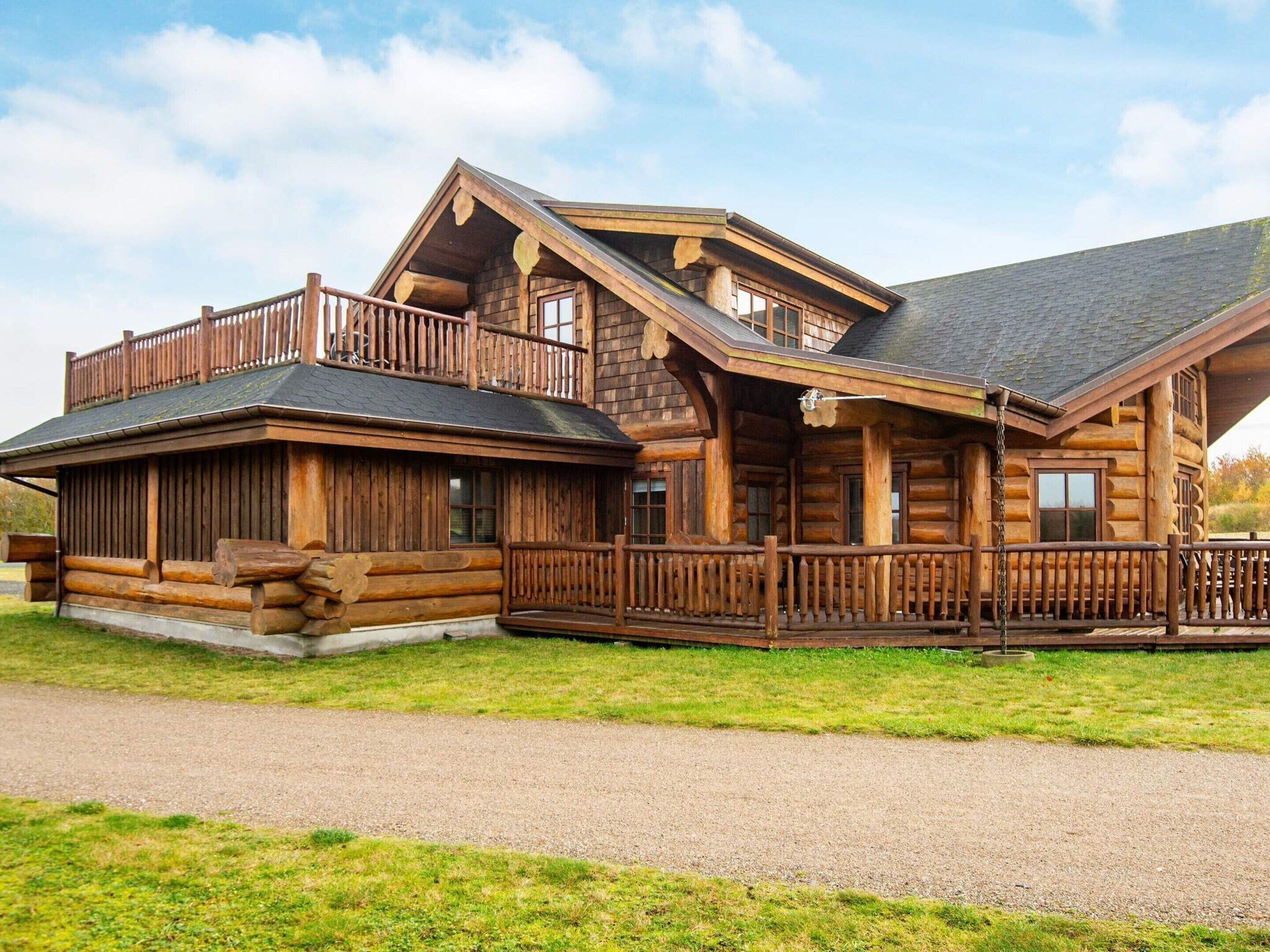 Eine Blockhütte mit Veranda, einer überdachten Terrasse und einem Schotterweg.