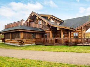 Eine Blockhütte mit Veranda, einer überdachten Terrasse und einem Schotterweg.