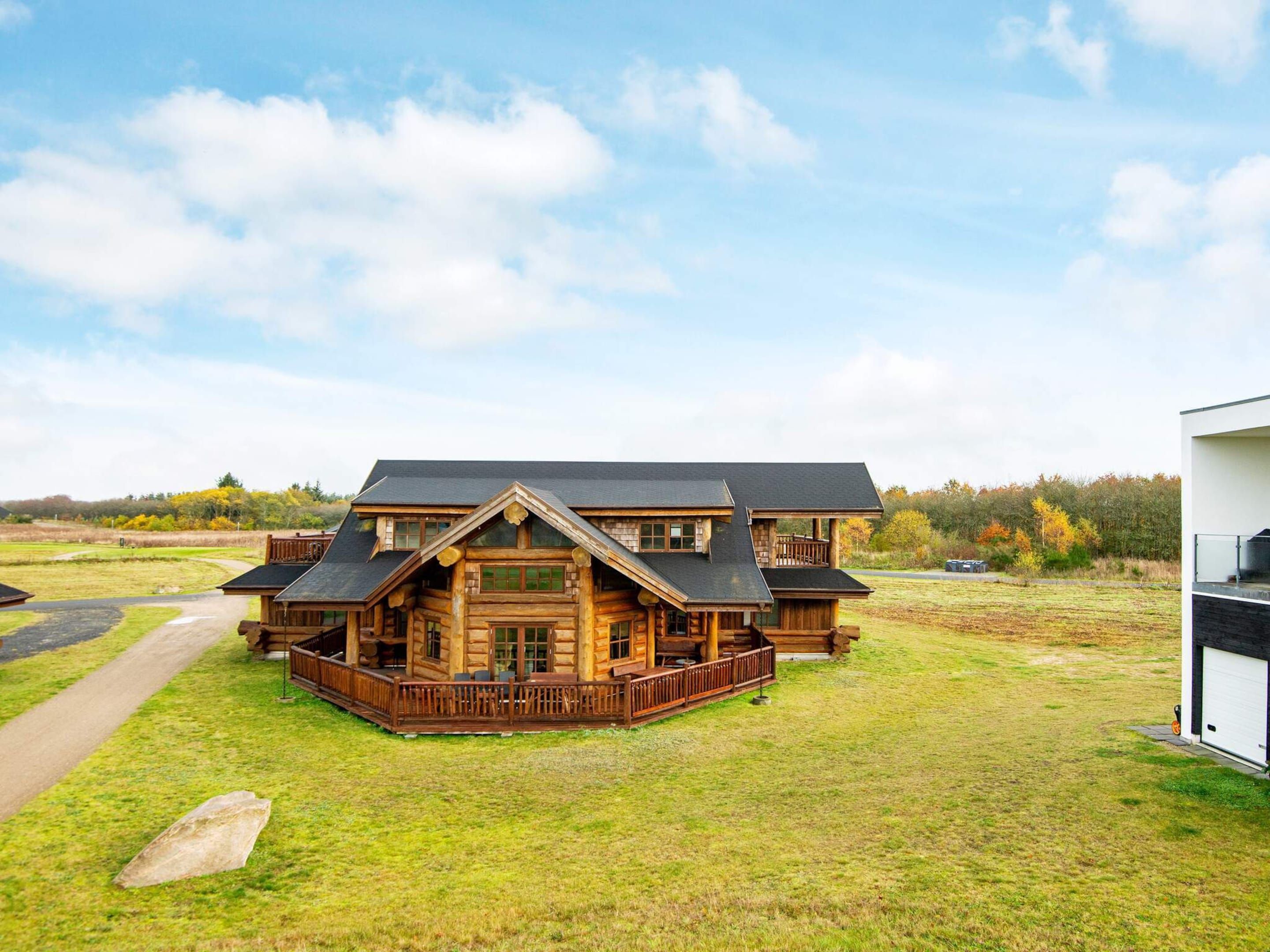 Eine Blockhütte mit Veranda, Garage und großem Rasen.