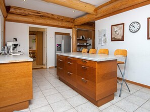 Eine Küche mit Holzausstattung, einem Edelstahlkühlschrank und einer Bar mit Sitzgelegenheiten.