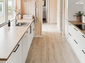 A modern kitchen with a wooden countertop, a sink, and cabinets.