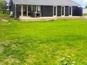Ein modernes Haus mit überdachter Terrasse und gepflegtem Rasen.