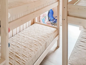 A bunk bed with a quilted mattress and a toy on the lower bunk.