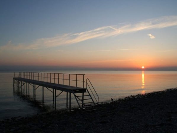 A pier extending into calm water during sunset.