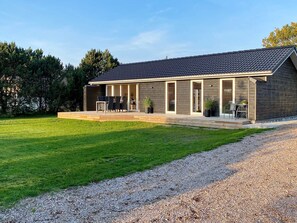 A modern house with a covered patio, a gravel driveway, and a well-maintained lawn. - 4 Star Holiday Home in Hadsund (Hadsund)