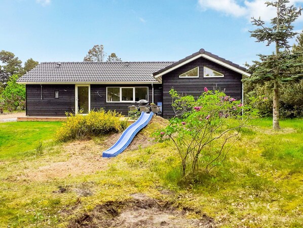 A house with a blue slide in the yard.