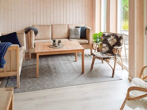 Ein modernes Wohnzimmer mit einer Couch, einem Couchtisch und einem Korbstuhl.