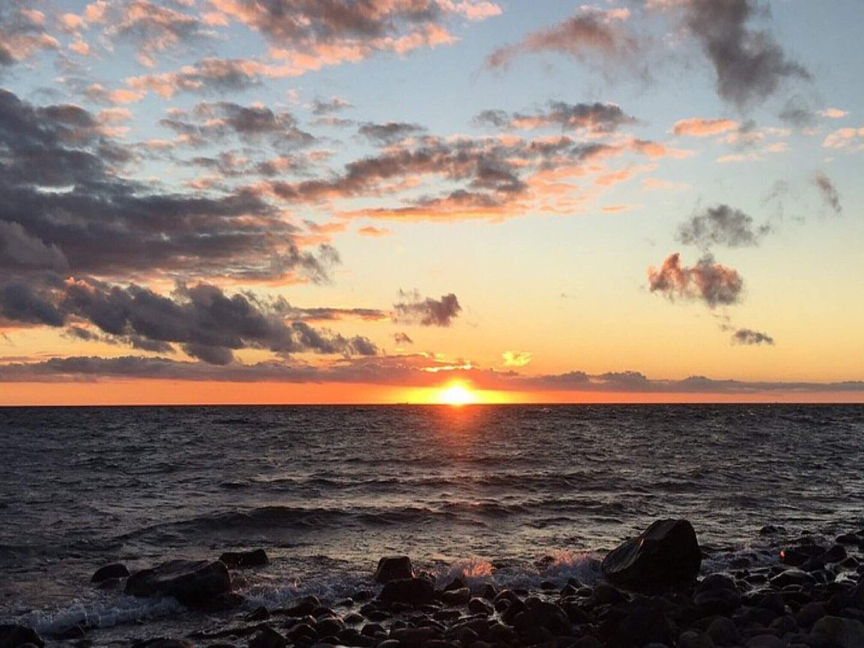 A sunset over a rocky shoreline with waves.