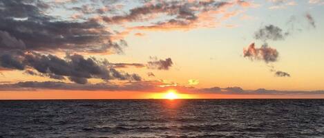 A sunset over a rocky shoreline with waves.