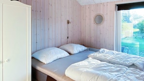 Un dormitorio con una cama, un aparador y una ventana con vista a follaje.