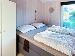 A bedroom with a bed, a dresser, and a window with a view of greenery.