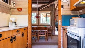 A wooden interior with a kitchenette, a dining area, and a view of the outdoors.