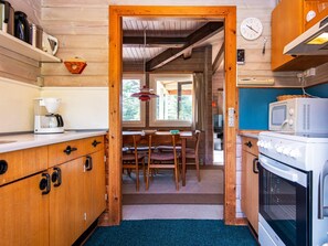 A wooden interior with a kitchenette, a dining area, and a view of the outdoors.