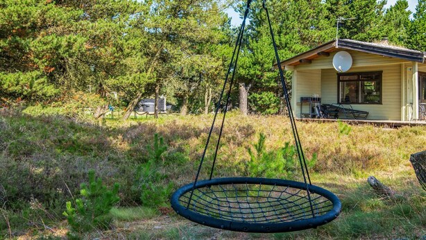 A house with a satellite dish, a swing, and a grassy yard.