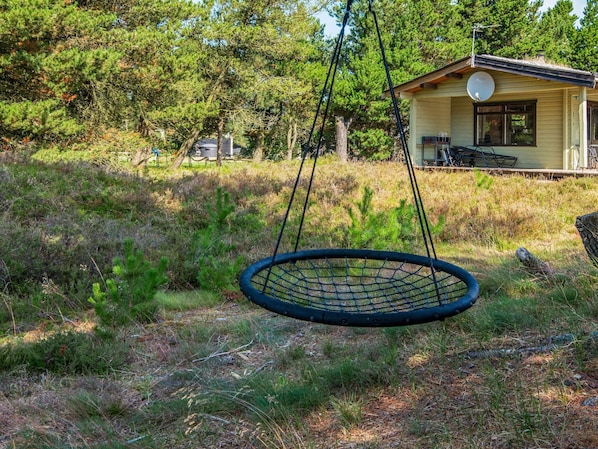 A house with a satellite dish, a swing, and a grassy yard.