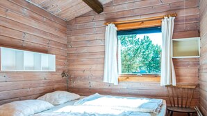 A cabin room with two beds, a window with curtains, and a small table.