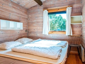 A cabin room with two beds, a window with curtains, and a small table.