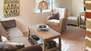 A cozy living room with a sofa, wicker furniture, a hanging light, and a wall sign. - 4 Star Holiday Home in Gotlands Tofta (Gotlands Tofta)