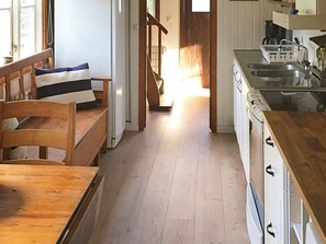A cozy kitchen with wooden cabinets, a sink, and a dining area with a bench and pillows.