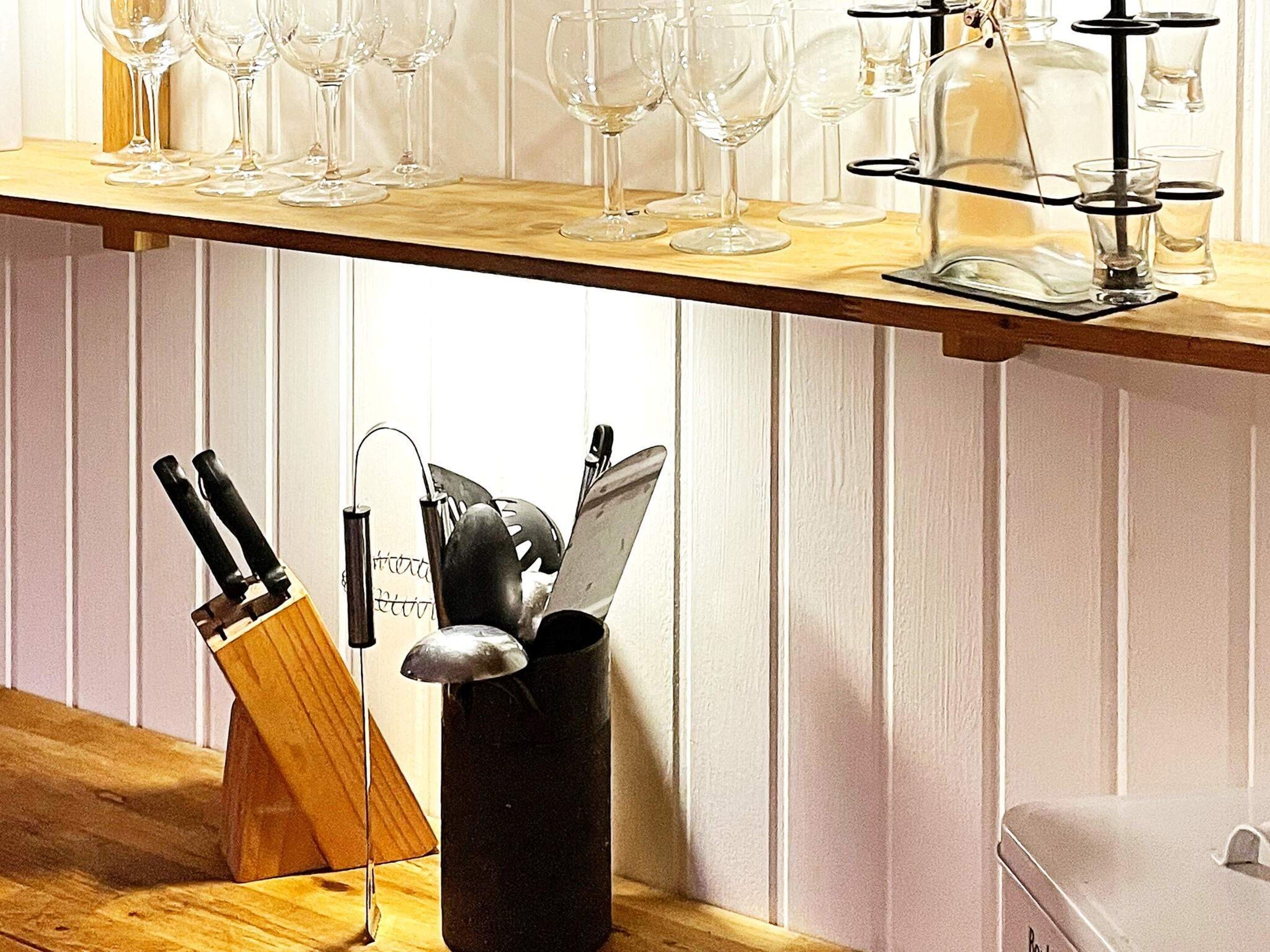 A kitchen counter with wine glasses and a knife block.